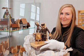 Schwarzenberger Weihnachtsmarkt: Sonderschau im Schloss - Museumsmitarbeiterin Vicky Seidel packt in einem Raum der Sonderausstellung eine Astarbeit aus, die zum Fundus des Museums gehört. Links sind einige der Miniaturhäuser zu sehen, die einen Großteil der Sonderschau prägen.