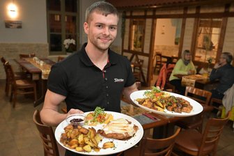 Schwieriger Start in Zwickau: Neues Restaurant hadert mit dem Ruf des Vorgängers - Kellner Jon Perthold serviert in der Schnitzelschmiede. Das Restaurant im Johannisbad ist der Nachfolger des früheren Schnitzelparadieses.