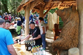 Sehnsucht und Neugierde sorgen für großen Andrang im Wald - In der neuen urigen Rasthütte, die als Getränkestand diente, hatten die Helfer des Heimatvereins einen großen Bären an ihrer Seite.