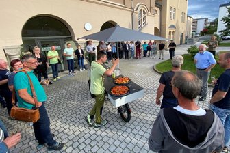 Sekt und Häppchen statt Zoff – Warum im Lengenfelder Stadtrat diesmal keine Fetzen flogen - Stadtrat in Lengenfeld mal anders. Als Bürgermeister Volker Bachmann (rechts im blauen Hemd) 19 Uhr noch immer allein im Ratssaal saß, schaute er draußen nach dem Rechten – und war für Sekunden sprachlos. Für Räte und Gäste hatte Ron Bauer (Mitte) auf dem Gastro-Bike gut gekühlte Getränke und Häppchen aus Waldkirchen mitgebracht.