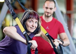 Selbstversuch Schlingen-Training: "Ich häng' mich rein" - Der Liegestütz im Schrägstand sieht einfach aus, ist es aber nicht, denn die Schlingen bieten keinen festen Widerstand beim Beugen und Strecken der Arme. Trainer Tom Andrä vom Studio 4everfitness in Chemnitz achtet bei Redakteurin Stephanie Wesely auf die korrekte Handhaltung. Er zeigt auf den kleinen Fotos drei Übungen am TRX zum Nachmachen.