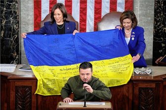 Selenskyj in Washington: "Ich bin sicher, dass wir diesen Krieg gemeinsam gewinnen" - US-Vizepräsidentin Kamala Harris (hinten links) und die Sprecherin des Repräsentantenhauses, Nancy Pelosi, breiten eine von Frontsoldaten signierte ukrainische Flagge aus, während Präsident Wolodymyr Selenskyj zu den US-Abgeordneten spricht.