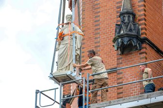 „Sie gehören zum Stadtbild“: Kran hebt Apostelfiguren an alten Platz an Nicolaikirche in Aue - Petrus schwebt per Kran an seinen alten Platz am Kirchenportal.