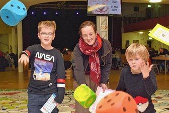 Siedler, Carcassonne & Co.: Stadthalle Limbach-Oberfrohna wird zum riesigen Spielbrett - Josephine Kapust testete bei der Spielenacht in der Stadthalle mit ihren Söhnen Peter (rechts) und Mattis ein Würfelspiel im XXL-Format. 