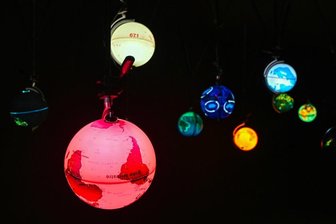 So ist die Ausstellung im Chemnitzer Spinnbau zur Medienkunstbiennale Pochen: Spaziergänge im Datendschungel - Ingo Günthers "World Processor" zeigt visualisierte Daten auf verschiedenen Globen, die in einem dunklen Raum leuchten.