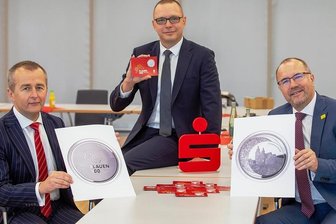 So sieht die Gedenkmünze zum Plauener Stadtjubiläum aus - Zum 900-jährigen Stadtjubiläum von Plauen gibt es eine Gedenkmünze aus Silber. Sparkassen-Vorstand Marko Mühlbauer, Sparkassen-Bereichsleiter Vertriebssteuerung Torsten Roscher und Plauens Oberbürgermeister Steffen Zenner (CDU/von links) stellten das Erinnerungsstück am Montag erstmals der Öffentlichkeit vor.
