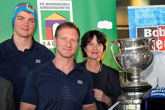 So viel kassiert das Bobteam um Francesco Friedrich für das Bauklötzchenhaus-Logo auf einer Mütze - Anschieber Simon Wulff (links) - hier neben Rekordweltmeister Francesco Friedrich und VSWG-Chefin Mirjam Philipp - wird das Logo des Marketingverbunds der sächsischen Wohungsgenossenschaften in der kommenden Saison auf seiner Mütze tragen.