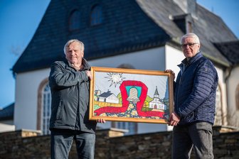 „Solche Momente vergisst man nie“ – Wie eine Glockenspende aus Brünlos eine bewegende Freundschaft nach Litauen brachte - Johannes Kunze (l.) sowie Hartmut Drechsel vom Verein Christliche Hilfe für Litauen mit einem gestickten Bild, das sie für die Partnerschaft von der Kirchgemeinde in Sakiai bekommen haben.