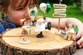 Sondereditionen zum Heimatfest in Grünhainichen: Elfpunkte-Engel wird selbst zum Holzspielzeugmacher - Die beiden Engel und das Blumenkind, das drei Grünhainichener Kunsthandwerksfirmen für das Jubiläum kreiert haben, bringen die vierjährige Nele Lehnert zum Strahlen.