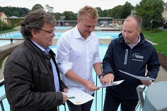 Sonne liefert Strom für Reichenbacher Freibad-Pumpen - Baufachbereichsleiter Sven Hörning, Chris Kummer, Junior-Chef von Elektro-Kummer, und Stadtwerke-Geschäftsführer Lars Lange (v. l.) im Freibad Reichenbach beim Blick in Unterlagen der Fotovoltaik-Anlage.