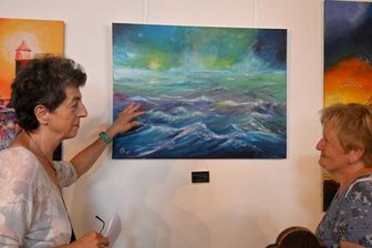 Spiel mit Farben und Hintergründen - Elke Müller (links) und Brigitte Malzdorf beim Betrachten von Bildern mit Seelandschaften in der Elterleiner Kirche. 