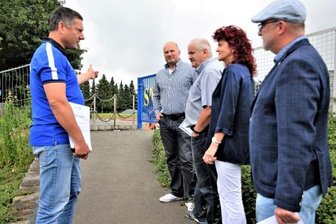 Sportler können digitale Anzeigetafel errichten - Ronny Röder (links), Vereinsvorsitzender des SV Coschütz, zeigt Frank Bilz vom Leader-Regionalmanagement und der Vorsitzenden der Lokalen Aktionsgruppe, Andrea Jedzig, die Fläche, auf der die Tafel aufgestellt werden soll. Am Ende des Weges entsteht gerade die neue Begegnungsstätte für den Ort. Mit im Bild: Sandro Bauroth (rechts), Bürgermeister von Elsterberg und Ortsvorsteher Andreas Oberlein (Mitte). 