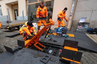Stadt Plauen erhöht Terrorschutz auf dem Weihnachtsmarkt: Mobile Durchfahrtssperren blockieren jetzt die Zufahrten - Bauhofmitarbeiter haben am Donnerstag die Durchfahrtssperren montiert. Das orangefarbene Sperrelement ist während der Öffnungszeit des Weihnachtsmarktes ausgefahren und blockiert die Zufahrt zum Festgelände.