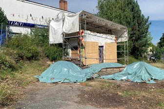 Stadt verbockt Tankstellenabriss: Arbeiten gestoppt - Es sieht aus wie eine letzte Bühne, bei der nur noch die Scheinwerfer fehlen: Die Reste der historischen Tankstelle wurden eingehaust, die schon abgebrochenen Materialien liegen unter Folie, das Gelände ist eingezäunt.