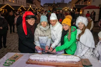 Stadtadvent Burgstädt: Neun-Kilo-Stollen innerhalb 20 Minuten für guten Zweck verkauft - Bürgermeister Lars Naumann, Gewerbevereinsvorsitzende Cornelia Scheibe, Bäckermeister Ullrich Rödel, Antje Warg vom Kinderheim in Burgstädt und Eiskönigin Jana Reiche (v. l.) schneiden gemeinsam einen 18 Pfund schweren Stollen an.