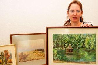 Stadtansichten kommen untern Hammer - Gabriele Arlt ist Mitarbeiterin des Pfarramtes. Sie zeigt die drei Bilder, die versteigert werden sollen.