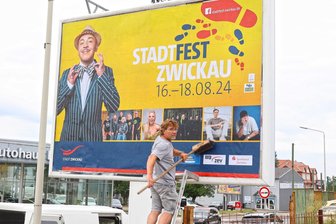 Stadtfest-Stargast Lou Bega soll als Posterboy Vorfreude auf Zwickaus größte Party wecken - Bauleiter Marco Pfitzner von Comedia Concept bringt ein Großflächenplakat in der Äußeren Dresdner Straße an.
