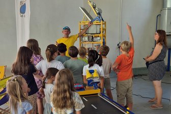 Stadtwerke Reichenbach begrüßen Kinder zum Entdeckertag - Nils Tiebel vom Neugier-Express erläutert Hortkindern der Kita Wichtelhausen eines der Experimente.