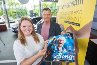 Stargast, Song-Premiere, Spitzen-Dirndl: Was das Plauener Spitzenfest 2025 zu bieten hat - Lena Schaller und Daniel Seifert vom Dachverband Stadtmarketing mit der Ankündigung für den Song „Spitz’nKidz“. Das Lied von Jonny Karacho soll am 21. Juni beim Spitzenfest in Plauen das erste Mal live gesungen werden.
