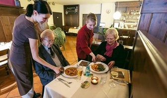 Starkoch-Ideen lassen Oederaner kalt - Kellnerin Silvia Schönherr (l.) und Nicole Bibrach (2.v.r.) servieren den Gästen ein Knoblauchsteak und Hähnchenmedallions. Die Oederaner essen lieber deftig sächsische Küche als Gourmetgerichte.Foto: Marcel Schlenkrich