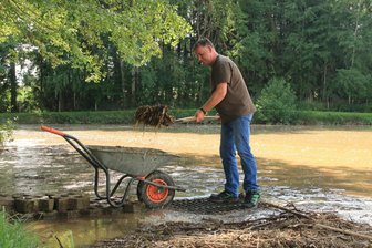 Starkregen im Vogtland: „Die Landwirte haben in den letzten Jahren viel gelernt“ - André Taubner und andere Helfer schaufelten nach dem Unwetter vom 31. Mai Schlamm, Geröll und Treibholz aus einem Treuener Teich.