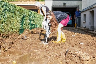 Starkregen überflutet im Erzgebirge Straßen und lässt Keller volllaufen - Eine braune, schlammige Masse ist in Adorf nach der Flut zurückgeblieben. Die Anwohner versuchen den Dreck zu beseitigen. 
