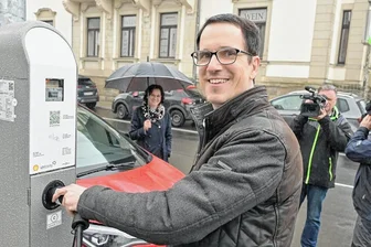 Steckdose in der Straßenlaterne: In Kirchberg können E-Autofahrer an der Straßenbeleuchtung auftanken - Daniel Schmidt vom Unternehmen Ubitri-City mitten im Medienrummel bei der Freigabe der Kirchberger Ladesäulen. Bürgermeisterin Obst hält sich im Hintergrund.