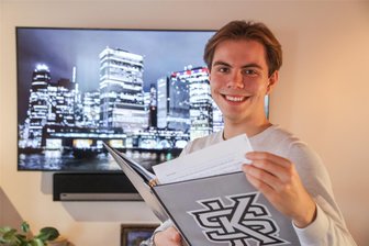 Stipendium öffnet Türen: Ein Claußnitzer in Amerika - Jonas Kertzsch hat für sechs Wochen in den USA in der Kennesaw State University im US-Bundesstaat Georgia studiert. Eine Stiftung ermöglicht dies. Hier hält er einen Hefter der Uni, dahinter die Skyline von New York. Der 18-Jährige lernt im Chemnitzer Rathaus.