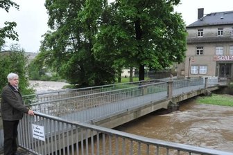 Stollberg/Burkhardtsdorf: Wassermassen wecken Ängste - In Burkhardtsdorf fehlt nicht mehr viel, bis die Zwönitz die Brücke zum ehemaligen Kino "Scala" überspült. Heinz Pechstein blickt besorgt auf das Geschehen. Die Brücke ist seit gestern drei Uhr gesperrt und bleibt es bis auf Weiteres.
