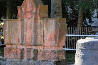 Stollberger Firma saniert Kriegerdenkmal - Das Denkmal auf dem Kirchhof in Neuwelt vor dem Abbau. Die Granitsteine bilden auch künftig den Sockel für die behauenen Porphyrblöcke. Der Standort wird beim Wiederaufbau leicht verändert.