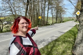 Streit um ein Ortseingangsschild im Erzgebirge: Zehn Meter hin oder her sorgen für Ärger - Gemeinderätin Anja Schieck zeigt auf das Ortseingangsschild, um das es geht.