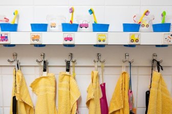            Handtücher und Zahnputzbecher hängen und stehen in einer Kindertagesstätte im Waschraum.