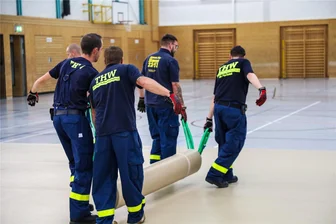 Tag der Sachsen in Aue: Sporthallen dienen einige Tage als Schlafsäle - Bodenbelag in Gemeinschaftsunterkünften: Zwölf Einsatzkräfte des THW begannen am Mittwochabend mit dem Verlegen des Belags, der auf drei Lkw verteilt war. Los ging’s in der Sporthalle in der Auer Neustadt.