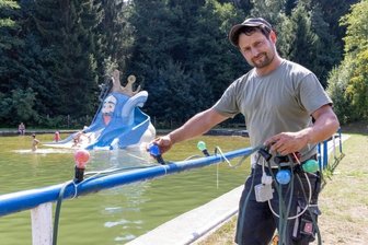 Tannenberg holt Fete im Naturbad nach - Vorbereitungen für die große Jubiläumsfeier am Wochenende: Tino Müller vom Bauhof der Gemeinde Tannenberg hängt die 80 Meter lange Lichterkette entlang der beiden Wasserbecken auf. 