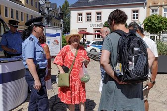 Tatort Wochenmarkt: Polizei berät in Annaberg zum Schutz vor Langfingern - Beratung zum Schutz vor Langfingern ganz praktisch: Polizeihauptmeisterin Kathy Seyferth erläutert Karla Rodriguez das richtige Tragen ihrer Umhängetasche.