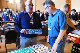 Tauschen, Feilschen, Fachsimpeln: Erzgebirge erlebt Europas größtes Treffen der Nummernschildsammler - Organisator Sven Rost (r.) schaut sich einige Nummernschilder des US-Amerikaners Jonathan Moore genauer an.