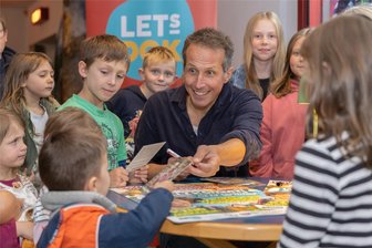Teenagerin trifft Willi Weitzel im Vogtland: „Ich musste mir unbedingt meinen Kindheitstraum erfüllen“ - Willi Weitzel im Auerbacher Kino von Kindern umringt: Als die Autogrammkarten alle waren, schrieb Willi seinen Namen auf Kinokarten und Kinderarme. So gut gefüllt war das Kino selten, freute sich auch Kinochefin Katharina Repp.