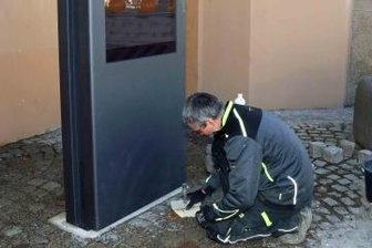 Terminal soll Touristen durch die Stadt lotsen - Mitarbeiter einer ortsansässigen Baufirma bei den letzten Arbeiten an der digitalen Informationstafel neben dem Rathauseingang.