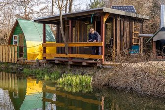 Test-Bewohner gesucht für Käppels neue Öko-Uferhütte - Haustechniker Mirko Buschner an der mit Daniel Glaw erbauten Uferhütte. Links das Kinder-Schlafiglu, rechts der innovative Grill-Kamin. Über einen von der Schlosserei Fleischmann gebauten Wärmetauscher wird Luft eingesaugt und via Rohr in die Hütte zum Heizen geleitet. Die Öko-Immobilie verfügt über einen separaten Zugang und Sonnenplatz.