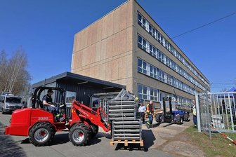 THW-Helfer bereiten in Meerane Unterkunft für Geflüchtete aus der Ukraine vor - Mit Gabelstaplern werden die Paletten mit den Metallbetten an das ehemalige Lehrlingswohnheim transportiert.