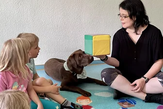 Tiergestützte Pädagogik im Erzgebirge: Es ist keineswegs nur Spielerei, wenn Kita-Hund Bella würfelt - Erzieherin Katja Voigt lässt Bella den Würfel anstupsen. Die Kinder schauen fasziniert zu.