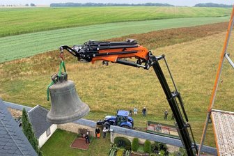 Topfseifersdorf lädt ein: Einmal Glocken anfassen, die über 500 Jahre alt sind - In luftiger Höhe hing die große Glocke im Juli 2022 am Kran vor der Kirche in Topfseifersdorf. Wie die kleine Glocke wurde sie aus dem Turm gehoben.