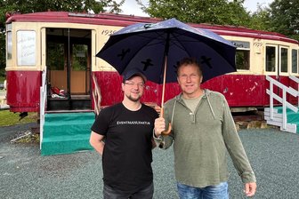 Tramway-Imbiss in Reichenbach öffnet am Freitag mit neuen Betreibern - Die Betriebsleiter Philipp Rosenkranz von Carlis Eventmanufaktur und Sven Rosenbaum vom Bereich Dienstleistungen und Hüpfburgen der DieLei gGmbH im Regen am Straßenbahn-Waggon.