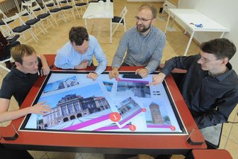 TU-Forscher eröffnen Lebendiges Labor in Chemnitzer Innenstadt - Arne Berger, Andreas Bischof, Michael Storz und Albrecht Kurze sitzen am Bildertisch, auf dem Fotos der Stadt angezeigt werden.