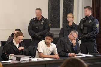 Türsteher in den Rücken gestochen: Prozessauftakt gegen brutale Jugend-Gang in Zwickau - Die Anklagebank im Schwurgerichtssaal war am Freitag mit fünf Angeklagten besetzt. Im Bild der Hauptangeklagte zwischen seinen Anwälten. Da er zurzeit in Untersuchungshaft sitzt, wurde er von Justizangestellten bewacht.