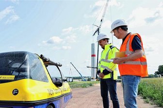 Turmbau zu Wiederau: Elektromobilfahrer trifft Windradbauer - Mit seinem Elektromobil hat Heinz Mampe an der Baustelle gehalten und von Projektleiter Philipp Wille (li.) und Stadtwerke-Sprecher Peter Krutsch erfahren, wie es mit Neubau weiter geht.