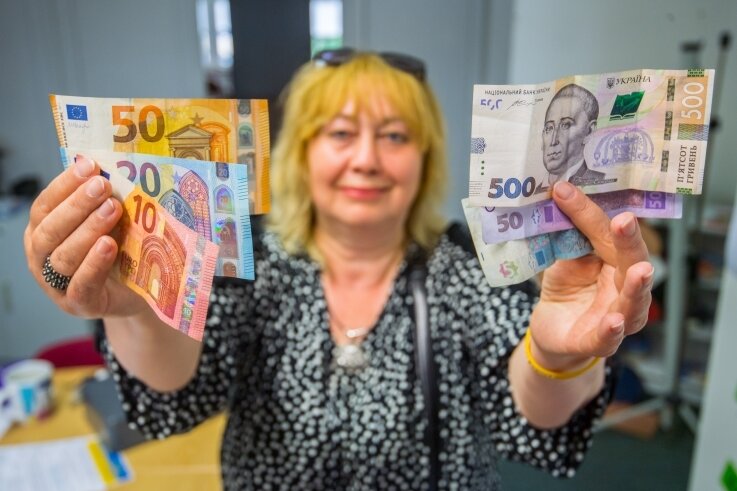 Ukrainer können im Erzgebirge jetzt Hrywnja in Euro tauschen - Tetjana Krykukha zeigt im Bürgerhaus Aue drei Euro- und Hrywnja-Scheine: Bislang war die ukrainische Währung nicht konvertibel. 