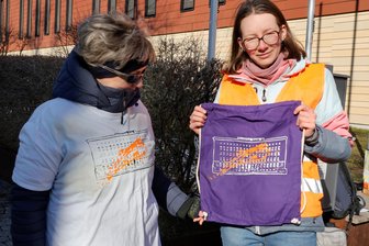 Umstrittener Protest in Chemnitz: Urteil gegen „Letzte Generation“ angefochten - Eine der in Chemnitz angeklagten Aktivisten der Letzten Generation (rechts) und eine Unterstützerin. Zur Finanzierung der Prozesskosten werden T-Shirts und Beutel mit einem Motiv des besprühten Gebäudes der Deutschen Bank am Chemnitzer Falkeplatz bedruckt.