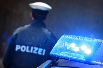 Ein Polizist steht vor einem Streifenwagen.