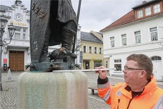Unbekannte wollten in Elsterberg zwei Meter große Brunnenfigur aus Bronze vom Sockel stürzen - Bauhofleiter Steffen Rinau zeigt auf die Stelle, an der die Diebe versucht haben, die Figur vom Sockel zu stoßen. Dort fehlt auch eine der Elstern, die bei Brunnenbetrieb das Wasser ausspeien.